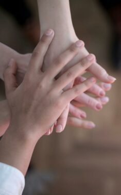 Hands stacked showing teamwork and unity from a top view indoors.