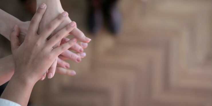 Hands stacked showing teamwork and unity from a top view indoors.